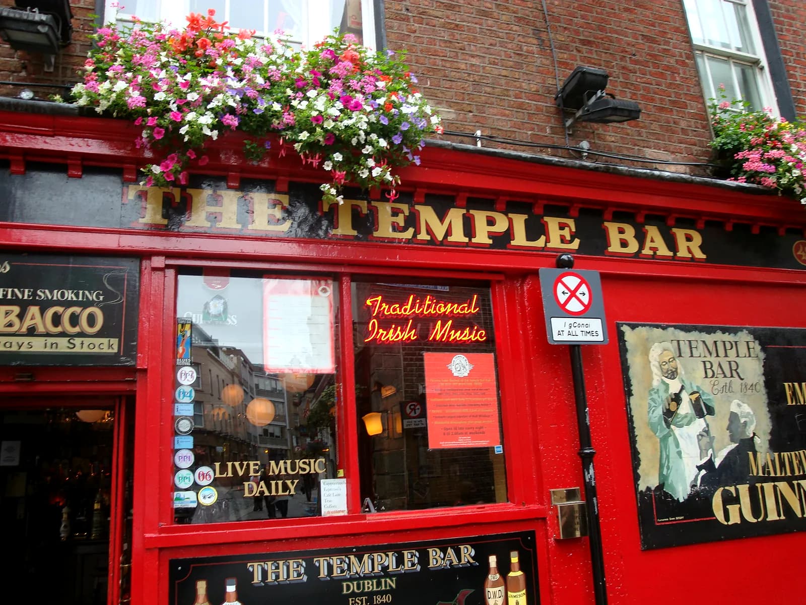 Fachada vermelha do pub The Temple Bar, em Dublin, decorada com flores